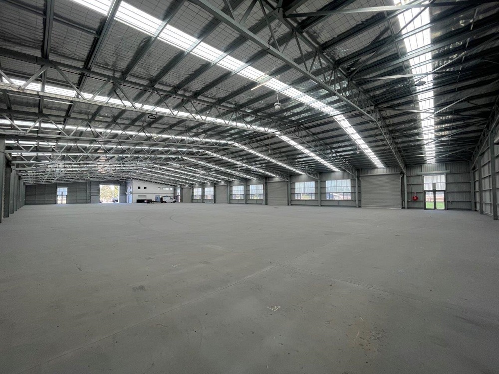 Spacious empty warehouse interior with metal roof structure