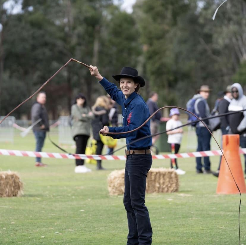 Person whip cracking at an outdoor event.